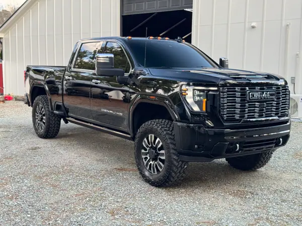 Black GMC Sierra Denali HD finished and gleaming on the gravel outside the AUTOGLOSS shop