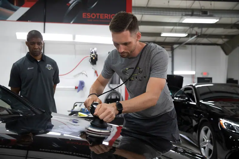 Jeff Miller machine-polishing a black hood during Esoteric's Elite Detailer training