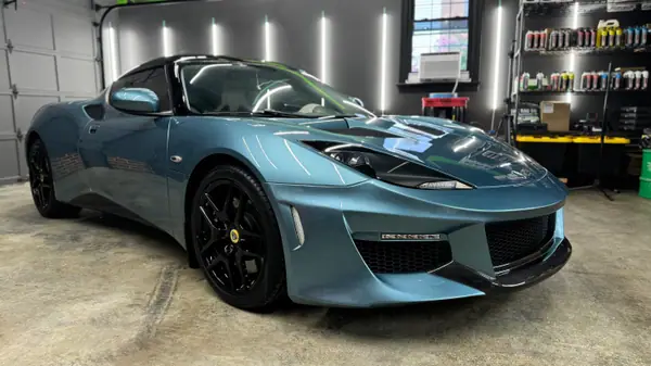 Ceramic-coated Lotus Evora in the AUTOGLOSS studio, the shop's green stripe reflected in the hood