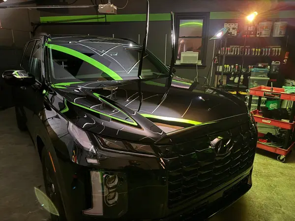 Black Hyundai Palisade hood after coating, reflecting the studio's green stripe