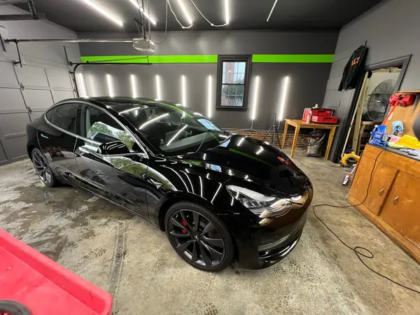 Black Tesla Model 3 in the studio after ceramic coating, light bars reflected in the paint